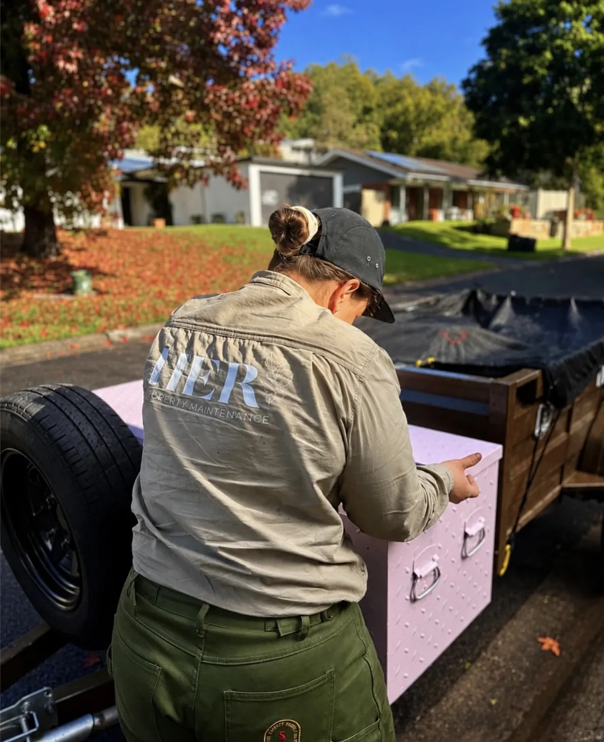 Female property maintenance professional in a luxury Australian garden at golden hour