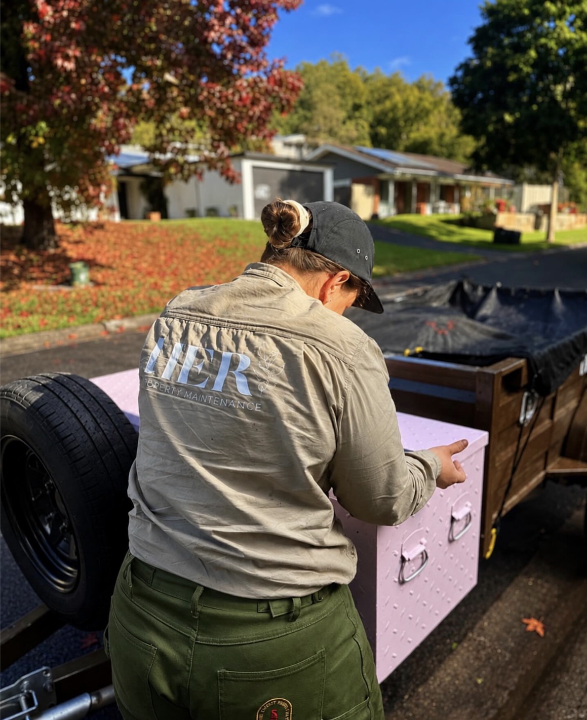 Female property maintenance professional in a luxury Australian garden at golden hour